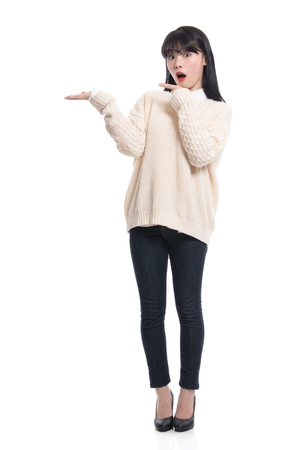 A studio portrait of a twenties Asian woman pointing at something and confidently introducingの写真素材