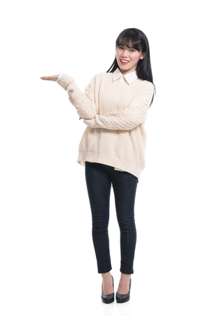 A studio portrait of a twenties Asian woman pointing at something and confidently introducingの写真素材