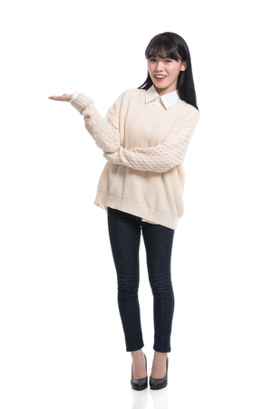 A studio portrait of a twenties Asian woman pointing at something and confidently introducingの写真素材