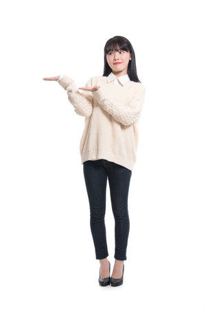 A studio portrait of a twenties Asian woman pointing at something and confidently introducingの写真素材
