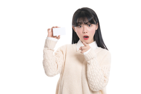 Asian female studio portrait surprised looking at cardの写真素材