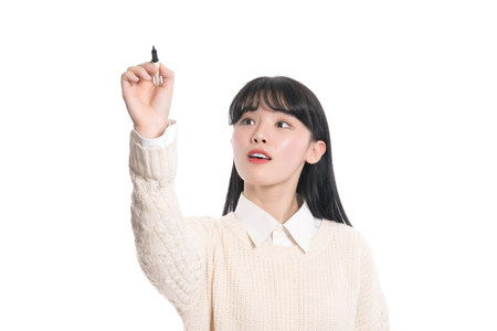 Studio portrait of twenties Asian woman writing something with a penの写真素材