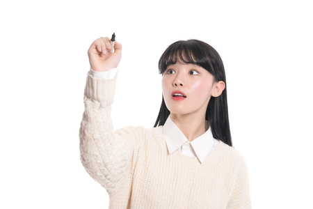 Studio portrait of twenties Asian woman writing something with a penの写真素材
