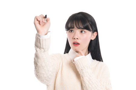 Studio portrait of twenties Asian woman writing something with a penの写真素材