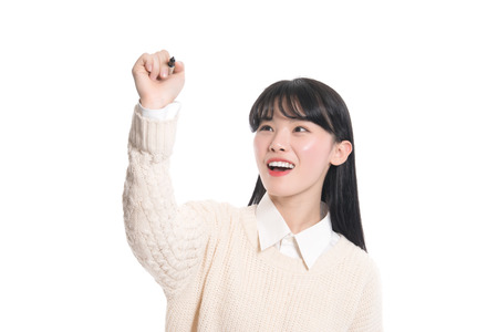 Studio portrait of twenties Asian woman writing something with a penの写真素材