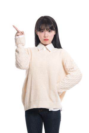 A studio portrait of a twenties Asian woman pointing at somethingの写真素材