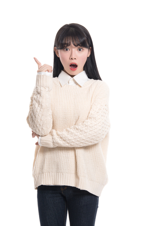 A studio portrait of a twenties Asian woman pointing at somethingの写真素材