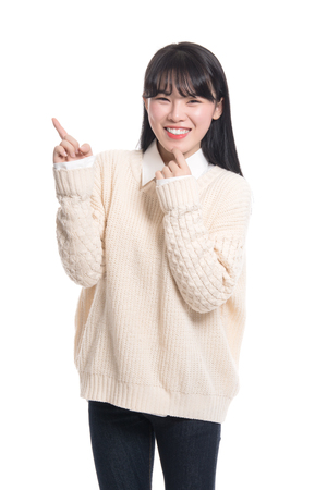 Studio portrait of twenties Asian woman pointing at something and being happyの写真素材