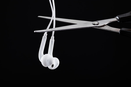 Scissors to cut earphones. Black backgroundの写真素材