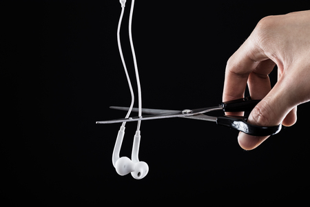 Scissors to cut earphones. Black backgroundの写真素材