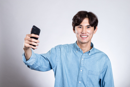 Studio portrait of a handsome asian man holding a smart phoneの写真素材