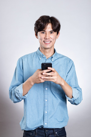 Studio portrait of a handsome asian man holding a smart phoneの写真素材