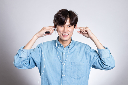Studio portrait of joyful asian man with smart phone and musicの写真素材