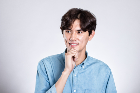Studio portrait of a handsome asian man having a happy worryの写真素材