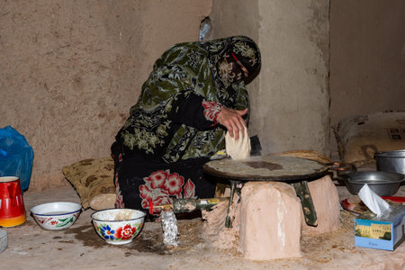 Omani woman in traditional dress preparing flatbread at Bait al Safah museum, Al Hamraのeditorial素材