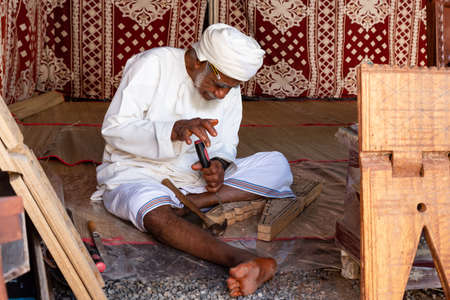Omani carpenter or wood carver working on a quran book rest called rehal in Nizwa fort, Omanのeditorial素材