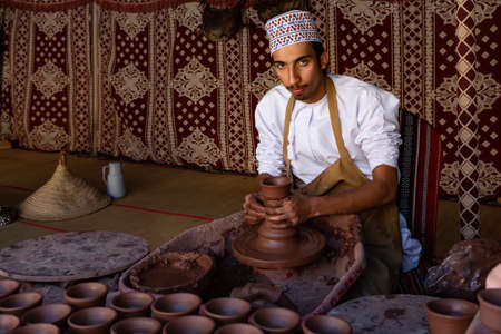 Omani potter working on his turntable, forming a bowl from clay with his hands in Nizwa fort, Omanのeditorial素材