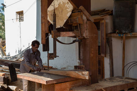 Sur, Oman - November 27 2019 Worker sawing ship planks in traditional dhow wharf in Sur, Omanのeditorial素材