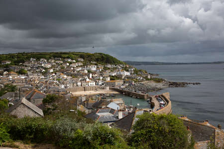 Dark clouds over Mousehole Harbor in Cornwall, UKの写真素材