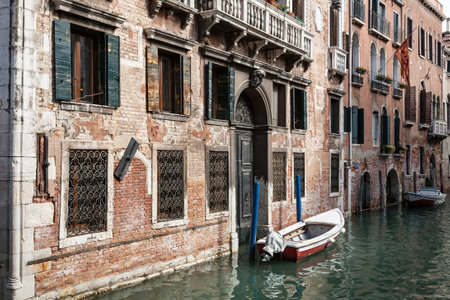 Typical venetian canal with a boat outside an old palazzo building, Venice, Italyの写真素材