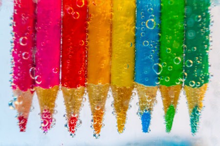 a row of colored pencils in sparkling waterの写真素材