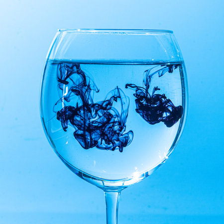 colorful ink drips into glass with water and creates beautiful streaks of color