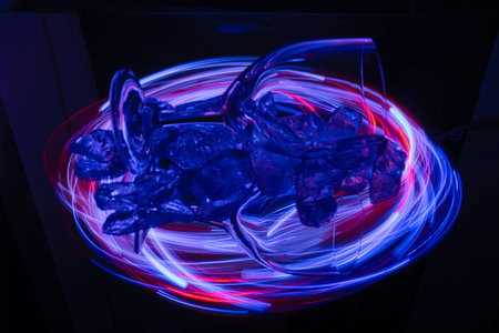 Painting with light on a mirror with small colored lamps and a drinking glass.