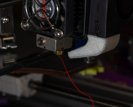 Close-up of a 3D printer with a red thread.