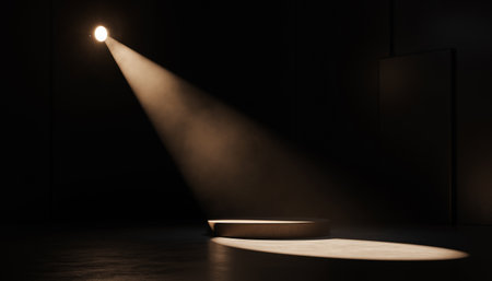 A spotlight shines down on an empty stage with a raised platform in a dark room.の素材