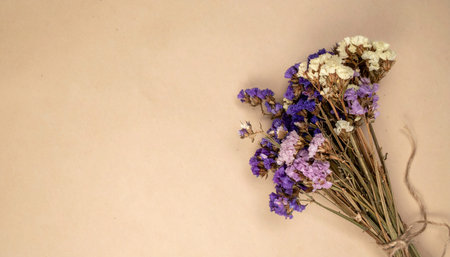 A bouquet of dried purple and white flowers tied with twine on a beige background