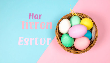 Pastel colored Easter eggs in a wicker basket on a split pink and blue background