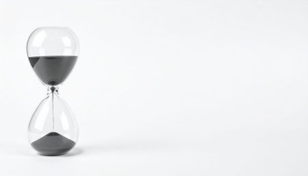 Isolated hourglass with sand flowing on white surface