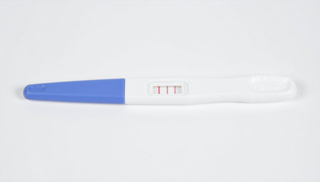 A pregnancy test kit with a blue cap on a plain white surface, indicating a medical or...