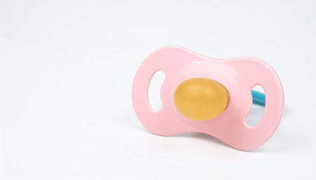 Isolated pink baby pacifier with yellow nipple on white surface