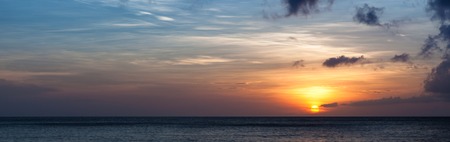 Setting sun over ocean horizon panorama viewの写真素材