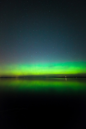 Beautiful northern lights aurora borealis over lake in finlandの写真素材