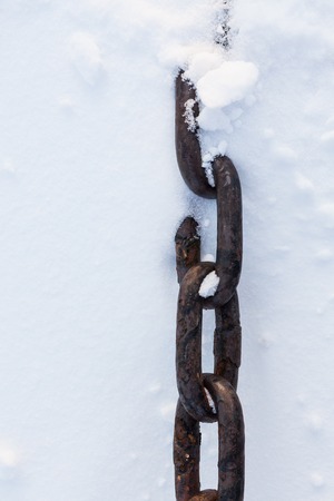 Strong chain partially buried in snow close-upの写真素材