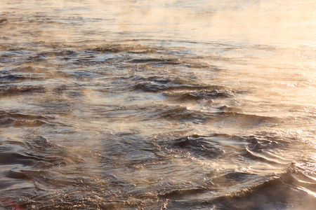 Water vapor on surface of cold icy water at sunny cold winter dayの写真素材