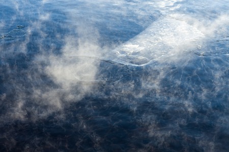 Water vapor on surface of cold icy water at sunny cold winter dayの写真素材