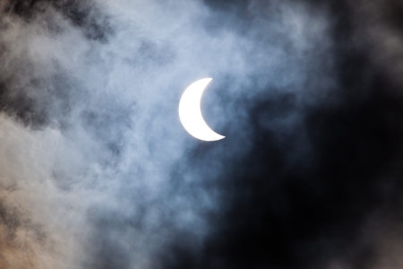 Partial solar eclipse viewed through clouds