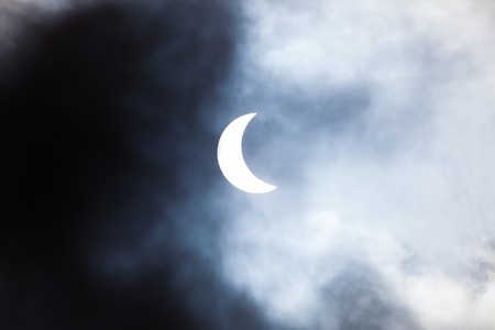 Partial solar eclipse viewed through cloudsの写真素材