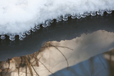 Small round icicles over water perfect reflectionの写真素材