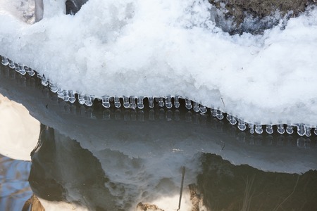 Small round icicles over water perfect reflectionの写真素材