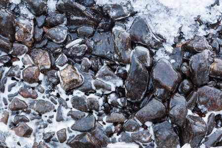 Small rocks covered in ice at lake shoreの写真素材