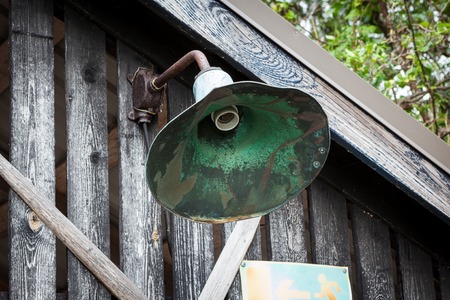 Metallic broken lamp in old wooden barn wallの写真素材