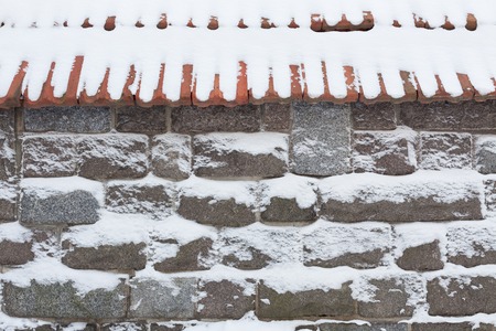 Stone wall and snow at winter day backgroundの写真素材
