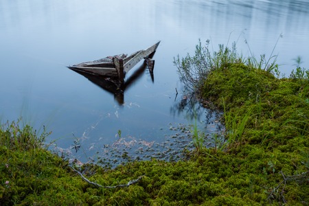 Sunken old rowboat abandoned in small forest lakeの写真素材