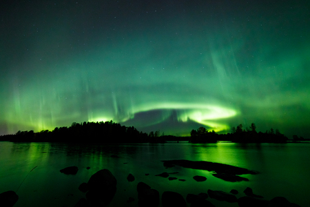 Beautiful northern lights aurora borealis over lake in Finlandの写真素材