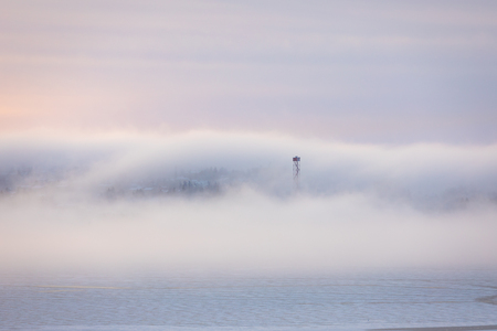 Dreamy thick fog at sunrise over hill and city buildingsの写真素材