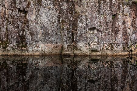 Rock reflectin to still water abstract in forest lakeの写真素材